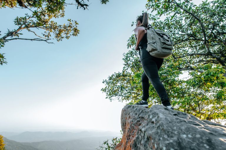 Rear view back of Young asian hiking female standing at view point and looking beautiful view with happy on peak mountain and sunray,  copy space
